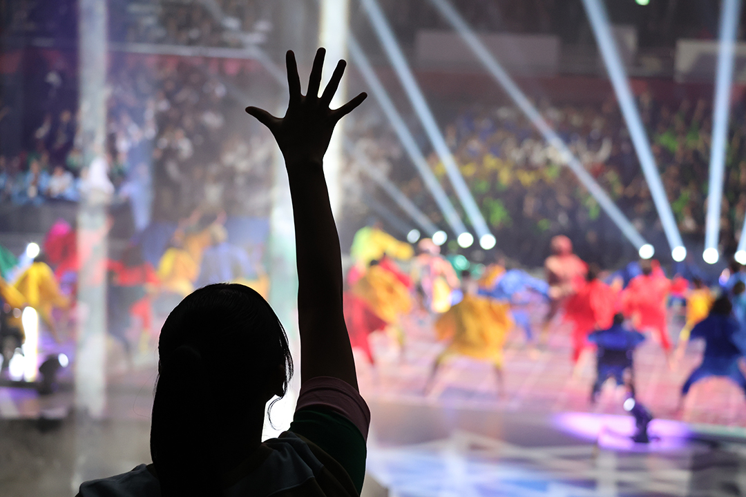 観客スタンドの通路で舞台と呼応するかのように踊るダンサーのシルエットが影のように見えます