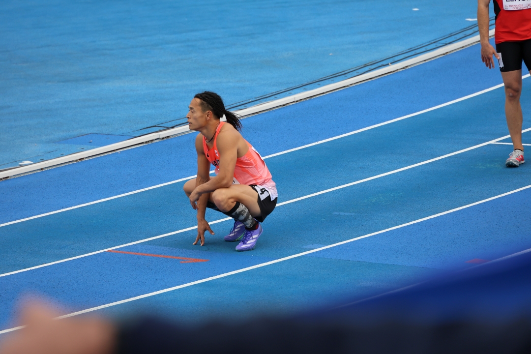 コースにしゃがみ込み結果を待つ佐々木選手