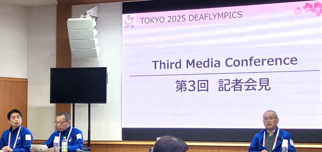 第3回記者会見のスクリーンを背景に、感動している久松委員長