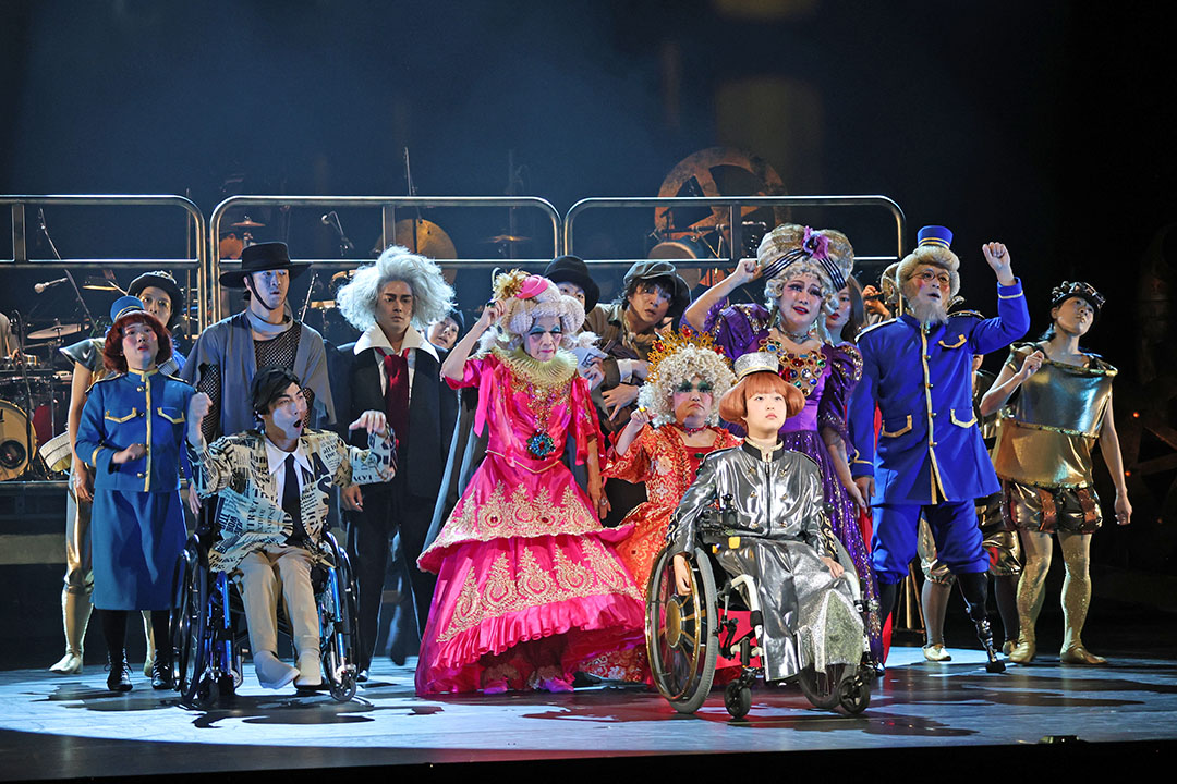 車いすの男女を前列に主要キャストがならんでいます
