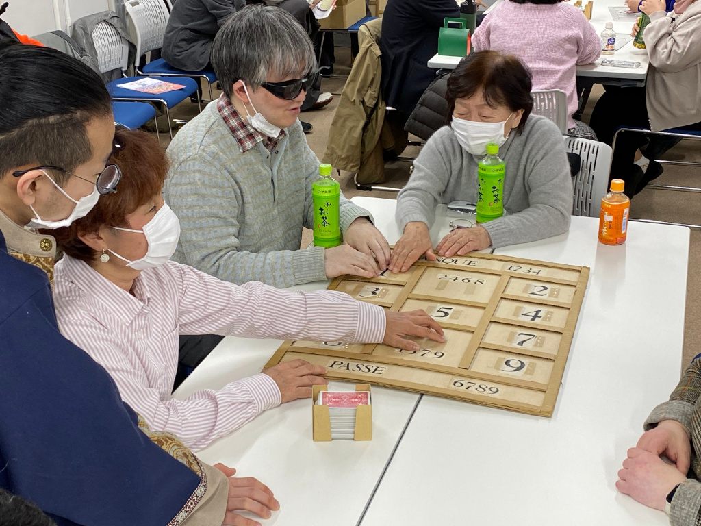 ボードゲームのボードに貼られた点字のシールを読み取る参加者たち