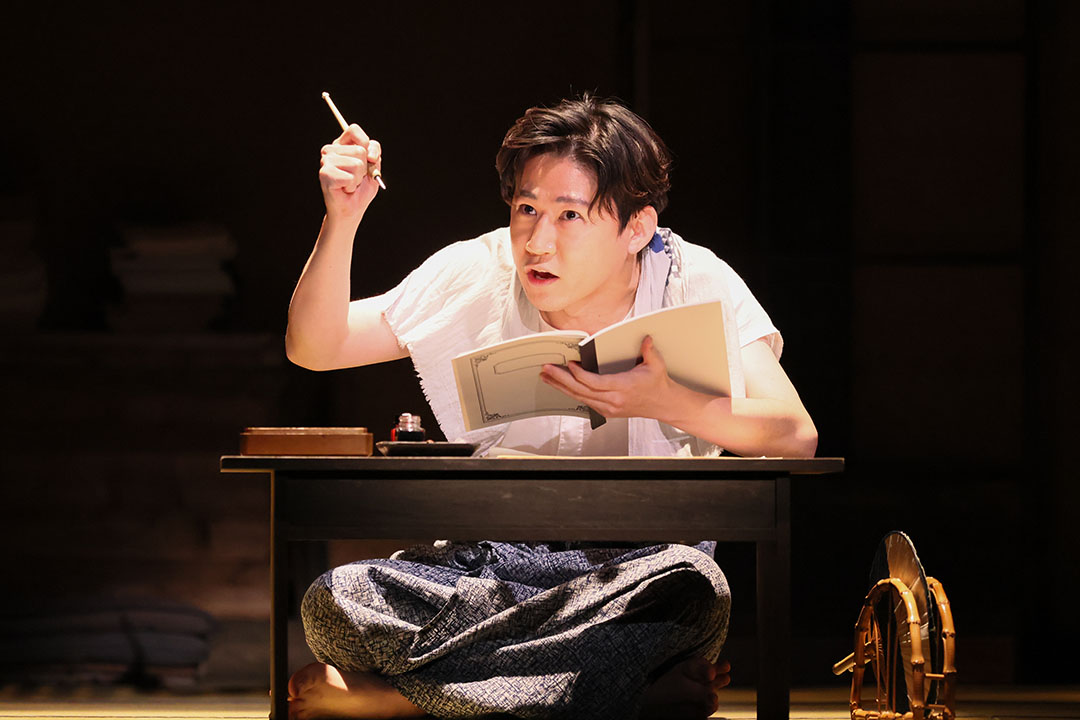 机に向かって執筆中の石川啄木